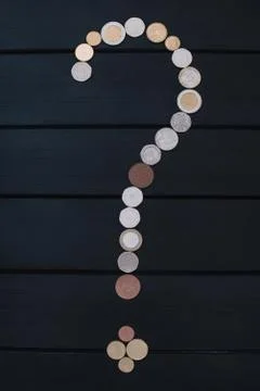 Scattered coins of different countries in the form of a question mark point o Stock Photos