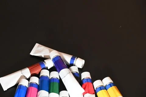 Scattered Colorful Paint Tubes on a Dark Black Background Stock Photos