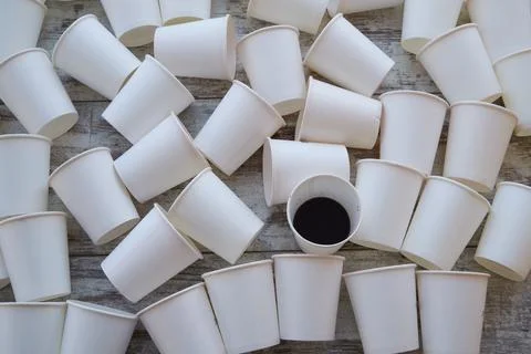 Scattered empty paper cups and one with unfinished coffee among them. Cheap s Foto stock