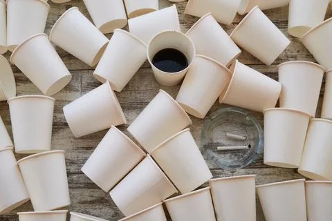 Scattered empty paper cups and one with unfinished coffee among them. Cheap s Stock Photos