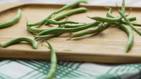 Scattered fresh green beans on a kitchen cutting board, close-up view Stock Footage 343555466