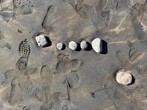 Scattered Medium Rocks on Sandy Beach Shoreline Stock Photos