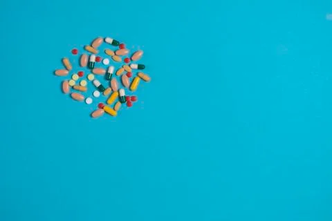 .scattered multicolored pills on a blue background with a place for copy spac Stock Photos