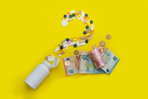 Scattered pills in the shape of a question mark next to euro banknotes and co Foto stock