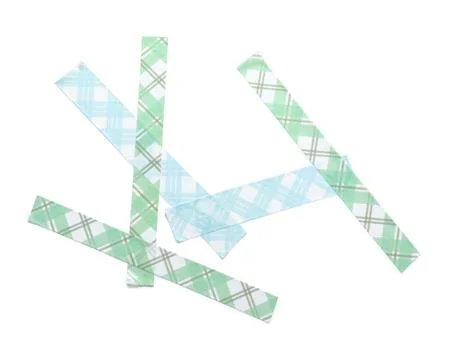 Scattered plaid patterned washi tape strips in green and blue on white backgr Stock Photos