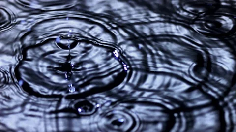 Scattered raindrops falling on a dark pool in ultra-slow motion Stock Footage 59529196