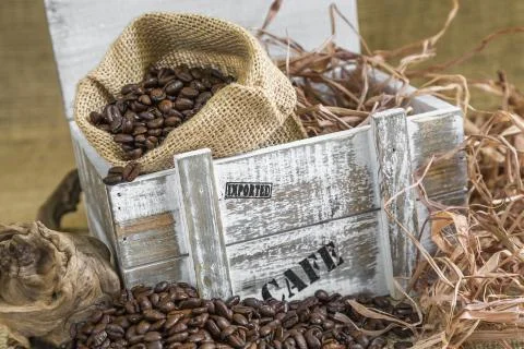 Scattered roasted coffee beans in front of old wooden box with a Fotos Stock
