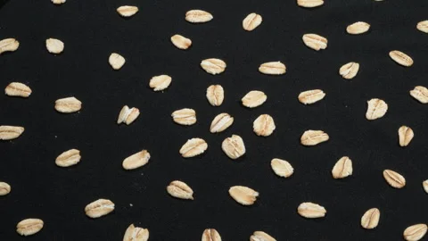 Scattered Rolled Oat Grains Rotating on Black Background. Video stock 333094480