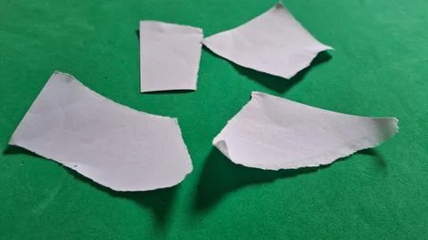 Scattered small pieces of torn white paper on green background Stock Photos