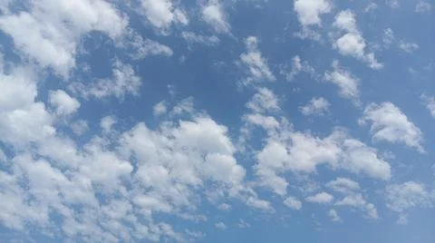 Scattered white clouds against a bright blue sky Stock Photos