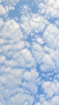 Scattered white clouds form a soft pattern across blue sky. Natural light c.. Stock Photos