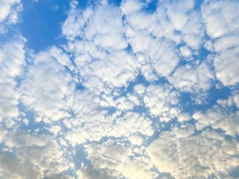 Scattered white clouds form a soft pattern across blue sky. Natural light c.. Stock Photos