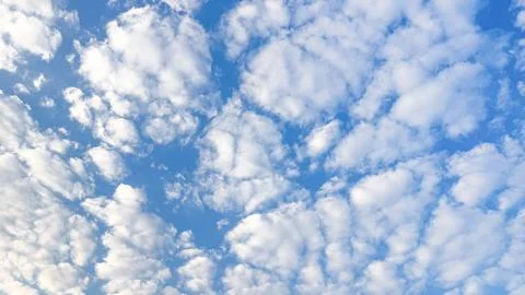 Scattered white clouds form a soft pattern across blue sky. Natural light c.. Stock Photos