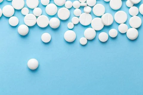 Scattered white pills on a blue table. Layout for special offers such as adve Stock Photos