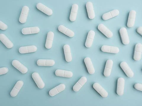 Scattered white pills on blue table. Mock up for special offers as advertis.. Stock Photos