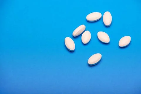 Scattered white tablets on a blue background Stock Photos