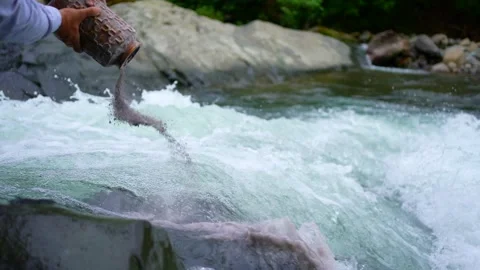 Scattering the ashes into the water after cremation in a beautiful mountain Stock Footage 247174080
