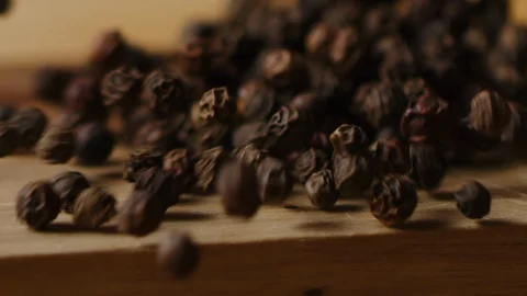 Scattering black pea pepper on kitchen table macro shot Stock Footage 128493274
