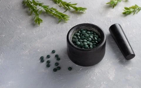 A scattering of Chlorella spirulina tablets on a gray background Stock Photos