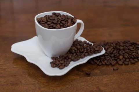 A scattering of coffee beans white cup and saucer Stock Photos