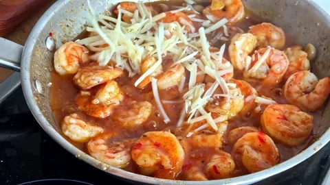Scattering grated cheese over Shrimp cooking in a pan with butter sauce Stock Footage 333779333