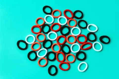 A scattering of multi colored elastic bands on a blue turquoise background Stock Photos