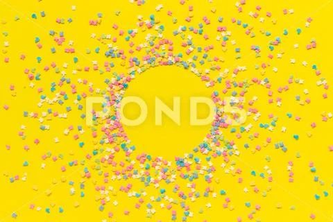 Scattering multicolored confectionery topping dressing on yellow paper. Circl Stock Photos