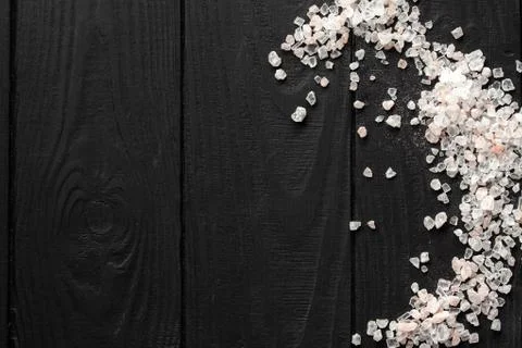 A scattering of pink Himalayan salt on a black wooden background. With place  Foto stock