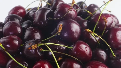A scattering of ripe black and red cherries with branches of shiny spinning.. 库存影片 296651901