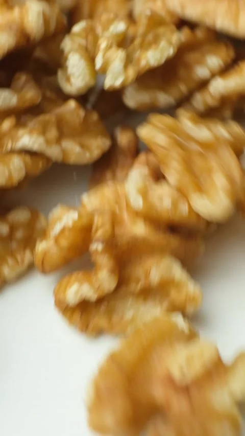 Scattering of walnut kernels on white background, macro vertical slow motion. Stock Footage 327087682