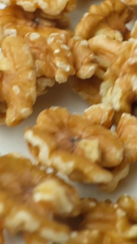 Scattering of walnut kernels on white background, macro vertical slow motion. Stock Footage 327376785