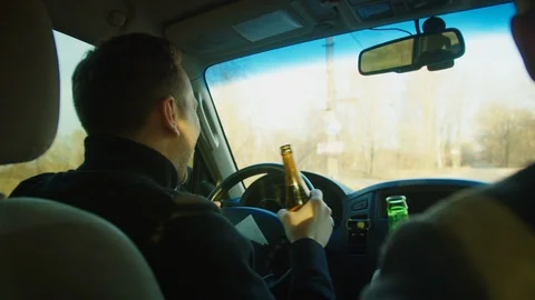 Scene in car .Two men are sitting in the car with bottles of beer, talking and l Stock Footage 121622005
