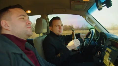 Scene in car .Two men are sitting in the car with bottles of beer, talking and l Stock Footage 121622344