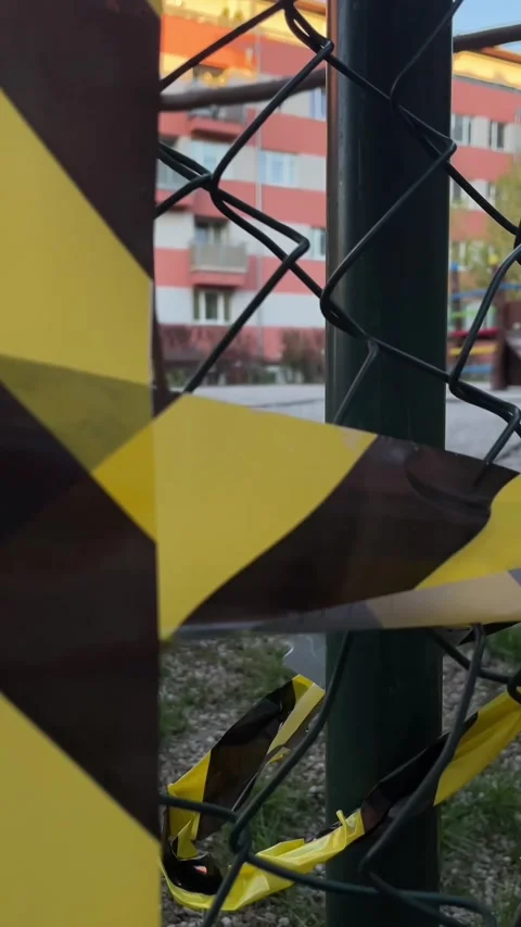 Scene of caution with frayed tape wrapped amidst city fencing at sunset Stock-Footage 341671586