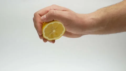 Scene of hand squeeze fresh lemon juice with white background Stock Footage 157554494