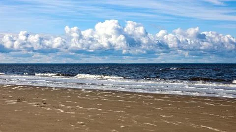 The scene includes a beach under a blue sky with clouds in the background Stock Photos
