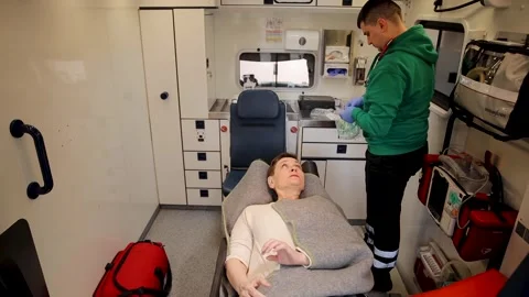 A scene inside an ambulance with a paramedic attending to a resting patient Video stock 305538251