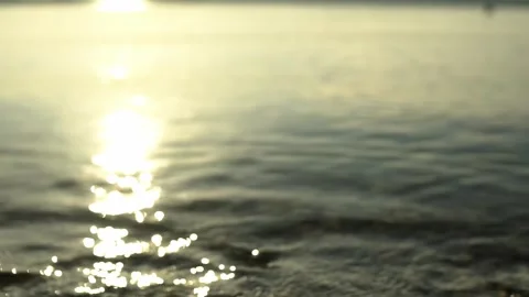 Scene of a lakeshore with pebbles in the lower foreground, reflection of the sun Video stock 248356483