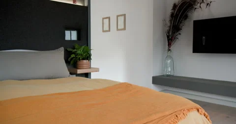 Scene opening begins camera panning past bed with orange throw and gray pillows Stock Footage 314028138