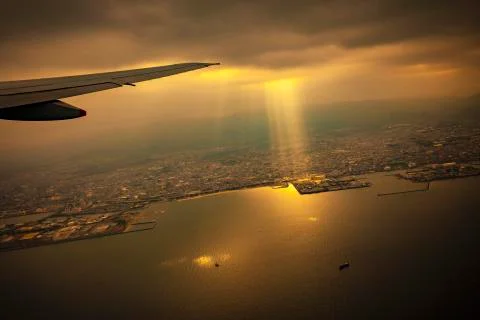 Scene from plane window of sun light ray through rain cloud over osaka town j Stock Photos