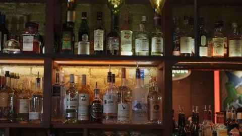 Scene Showcasing Diverse Spirits On Backlit Wooden Shelves With Vibrant Lighting Stock Footage 323897959