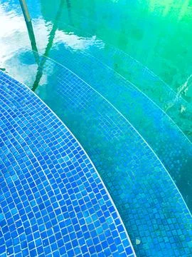 The scene shows blue tile steps leading into a pool filled with clear water.  Stock Photos