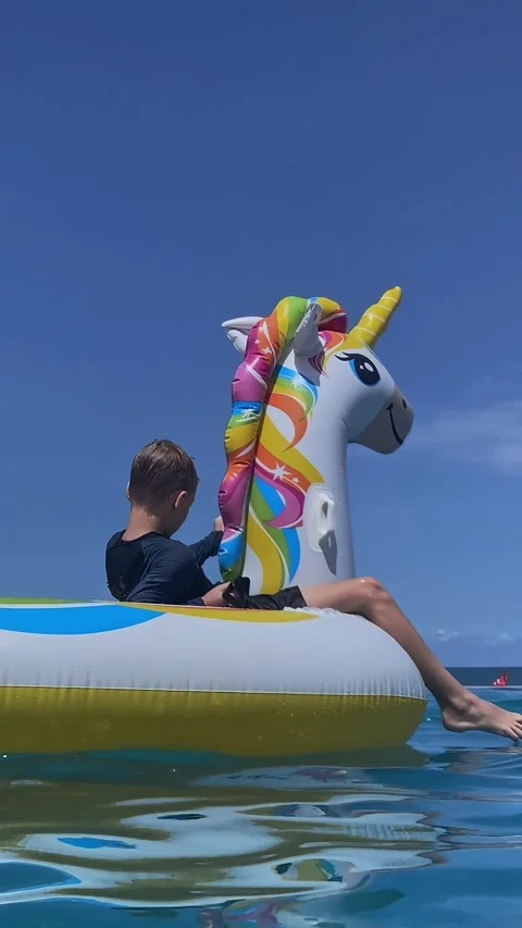 Scene shows children on unicorn float in turquoise sea with snorkel gear 스톡 동영상 336638695