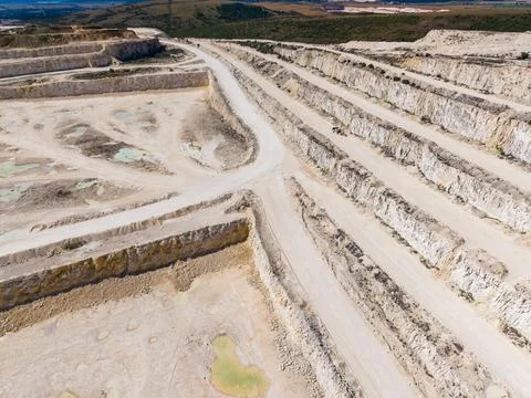 The scene shows a large quarry with deep cuts in the ground. Dirt paths lead  Stock Photos