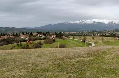 Scene with springtime mountain glade, forest, snow and residential district Stock Photos