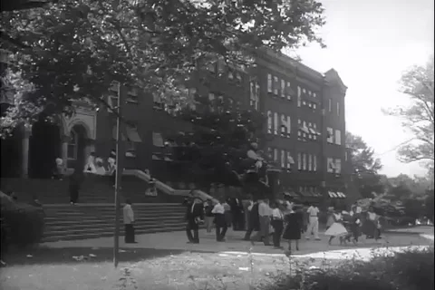 Scene of students leave school campus and walk on a sidewalk - 1960 Stock Footage 105685347