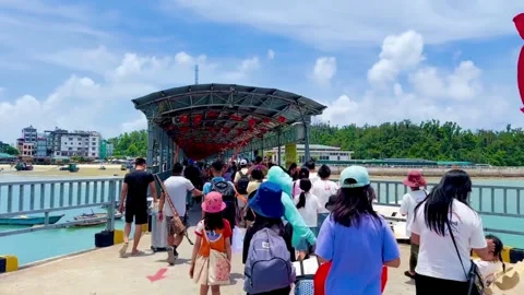 Scene of tourists leaving the pier looking towards the busy coastal town Stock Footage 327802470
