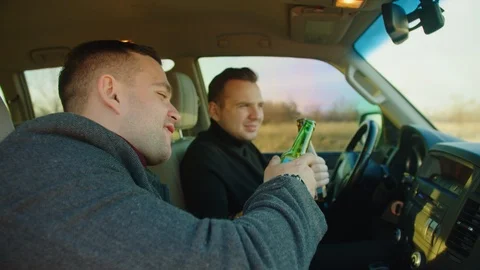 Scene of two men ride in a car with bottles of alcohol, they drink alcohol while Stock Footage 121620977