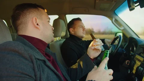 Scene of two men ride in a car with bottles of alcohol, they drink alcohol while Stock Footage 121622824