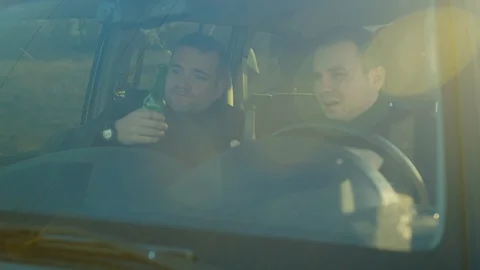 Scene of two men ride in a car with bottles of alcohol, they drink alcohol while Stock Footage 121623408